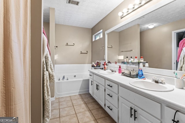 bathroom with a garden tub, a textured ceiling, a sink, tile patterned floors, and double vanity