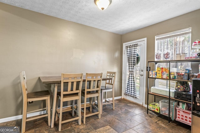 dining room with stone finish floor, a textured ceiling, and baseboards