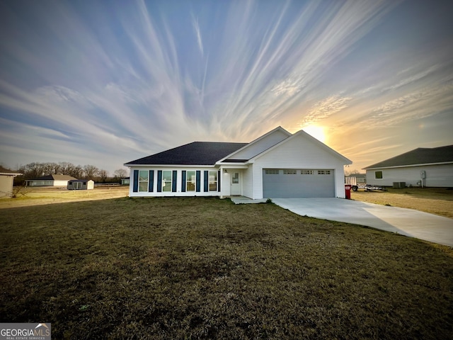 ranch-style house featuring driveway, an attached garage, and a yard