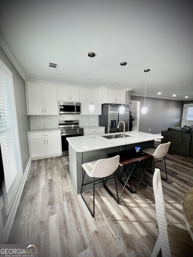 kitchen featuring stainless steel appliances, visible vents, decorative backsplash, white cabinets, and a sink