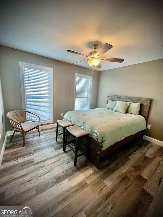 bedroom with a ceiling fan, baseboards, and wood finished floors