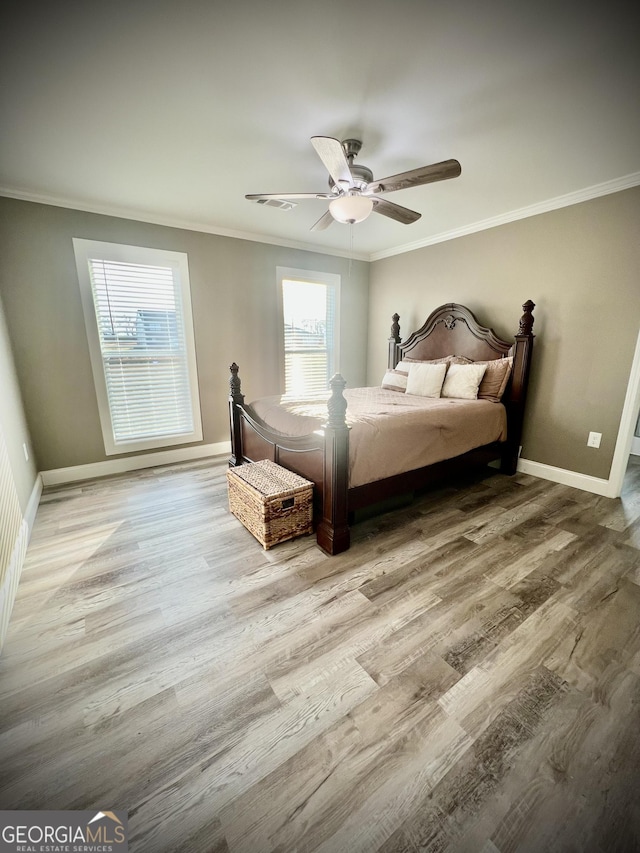 bedroom featuring a ceiling fan, crown molding, baseboards, and wood finished floors