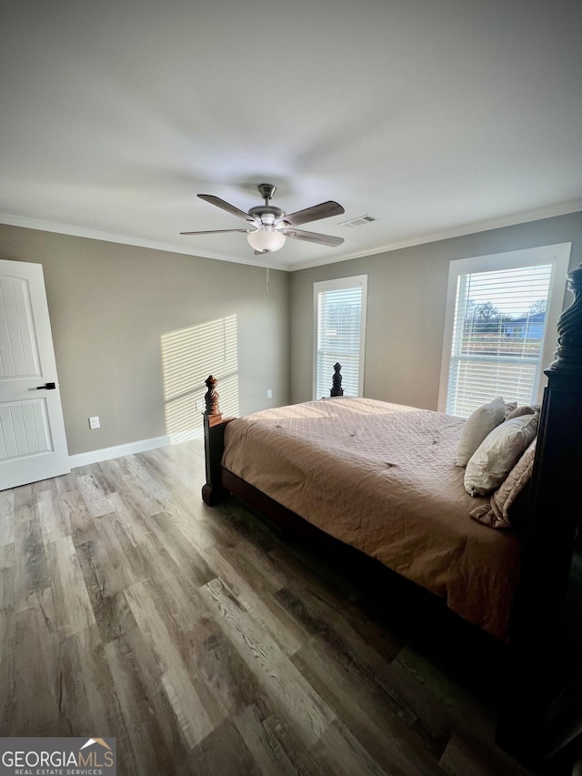 bedroom featuring multiple windows, wood finished floors, visible vents, and crown molding