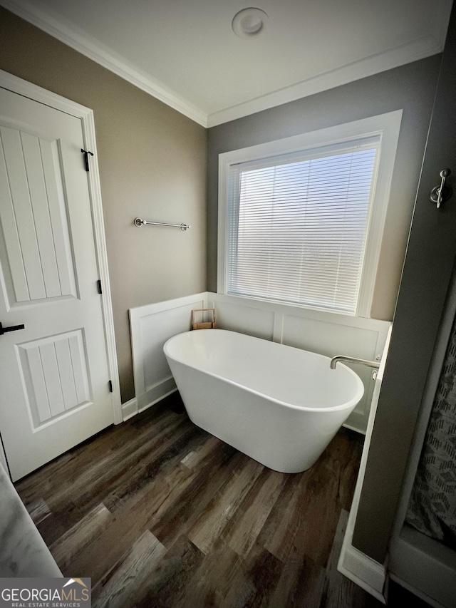 full bath featuring ornamental molding, a soaking tub, and wood finished floors