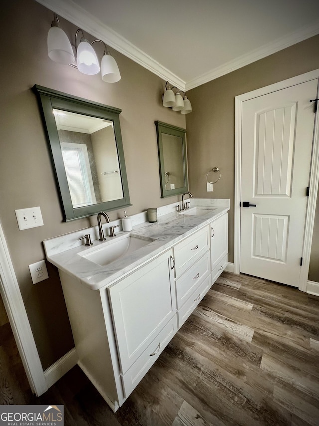 full bathroom with ornamental molding, a sink, baseboards, and wood finished floors