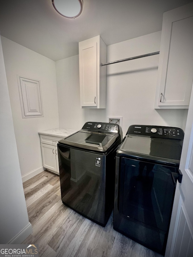 laundry room with light wood-type flooring, washing machine and dryer, cabinet space, and baseboards