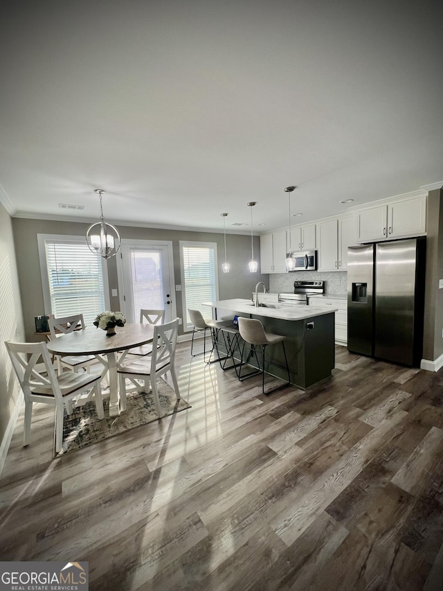 dining room with ornamental molding, dark wood finished floors, baseboards, and an inviting chandelier