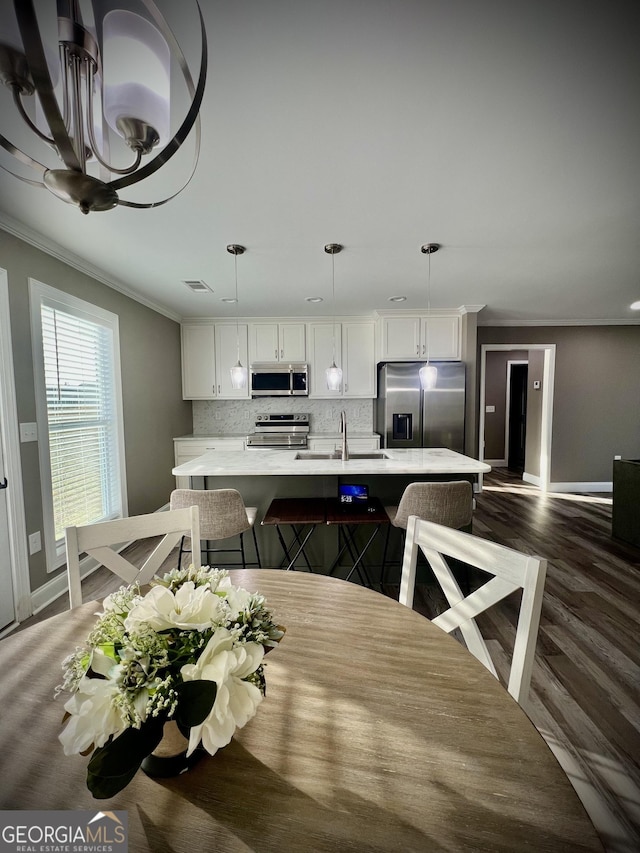 dining space featuring ornamental molding, wood finished floors, visible vents, and baseboards