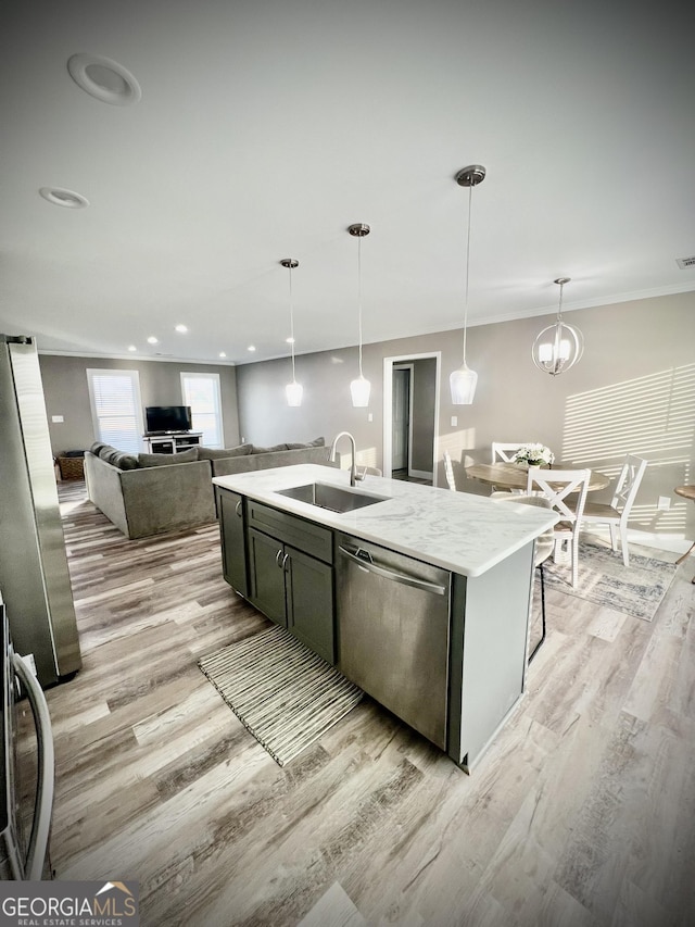 kitchen with dishwasher, a center island with sink, a sink, and light wood-style flooring