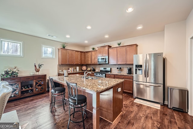 kitchen featuring dark wood-type flooring, visible vents, stainless steel appliances, and light stone counters