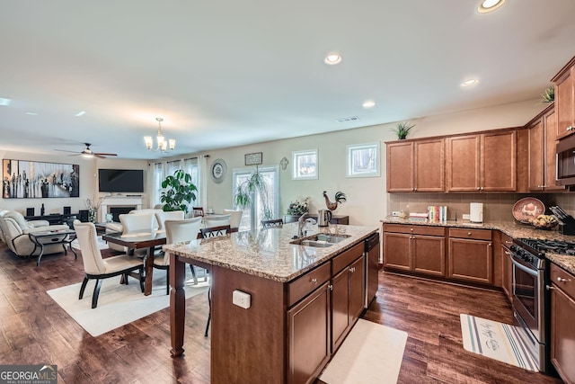 kitchen with stainless steel appliances, a fireplace, a sink, decorative backsplash, and dark wood-style floors