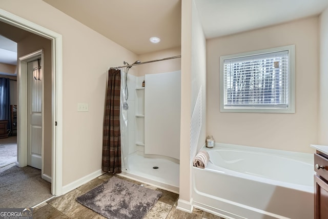 bathroom with a stall shower, a garden tub, and baseboards