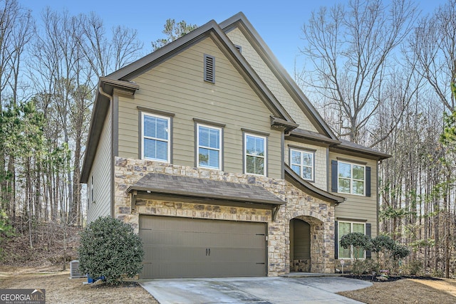 view of front of house with driveway, stone siding, an attached garage, and cooling unit