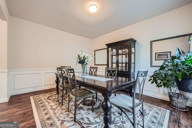 dining room with a decorative wall, dark wood finished floors, and wainscoting