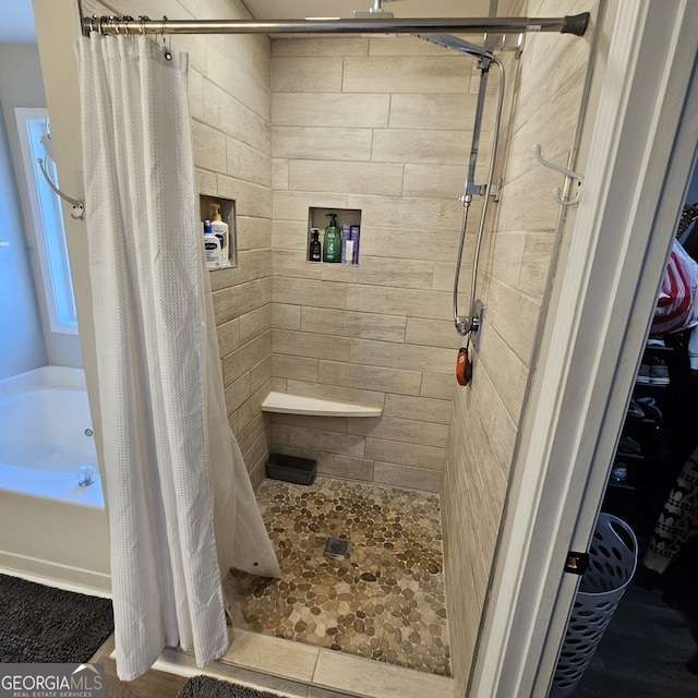 bathroom featuring a tub to relax in and a shower stall