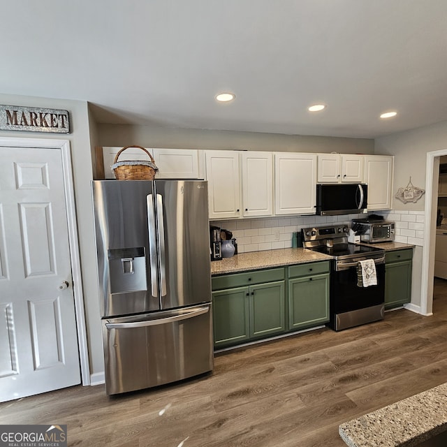 kitchen featuring stainless steel appliances, wood finished floors, white cabinetry, and green cabinetry