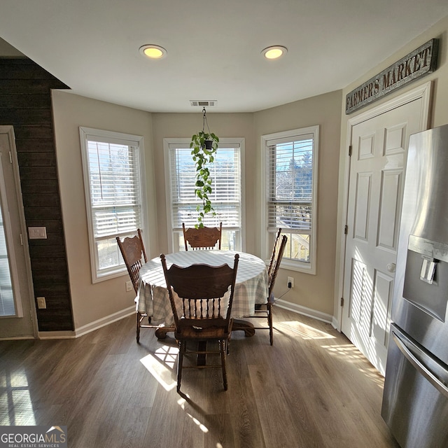 dining area with a wealth of natural light, baseboards, visible vents, and dark wood-style flooring