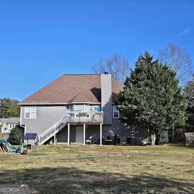 rear view of house featuring a deck, stairway, a chimney, and a lawn