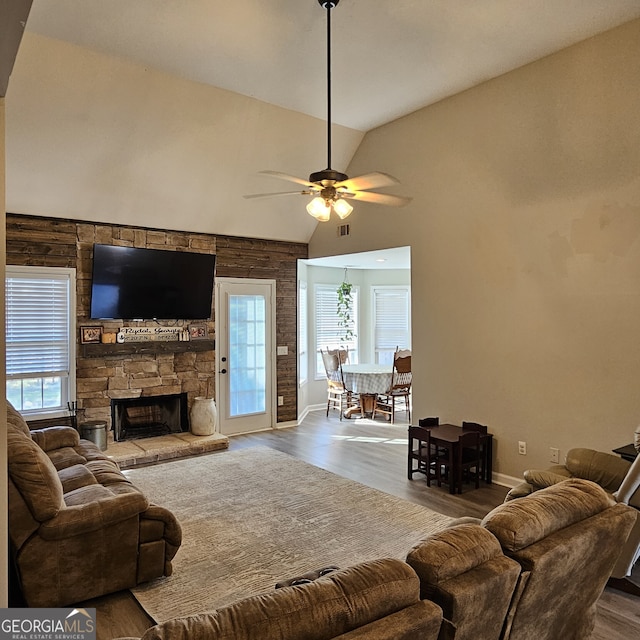 living room with visible vents, a ceiling fan, wood finished floors, a fireplace, and high vaulted ceiling