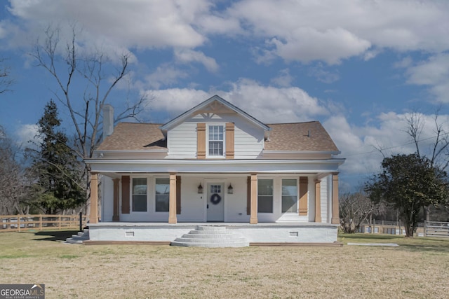 bungalow-style house with covered porch, a shingled roof, fence, a front lawn, and a chimney