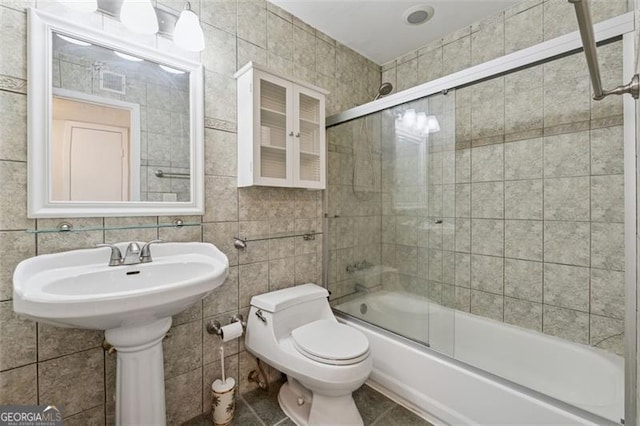 full bathroom with toilet, enclosed tub / shower combo, tile walls, and tile patterned floors