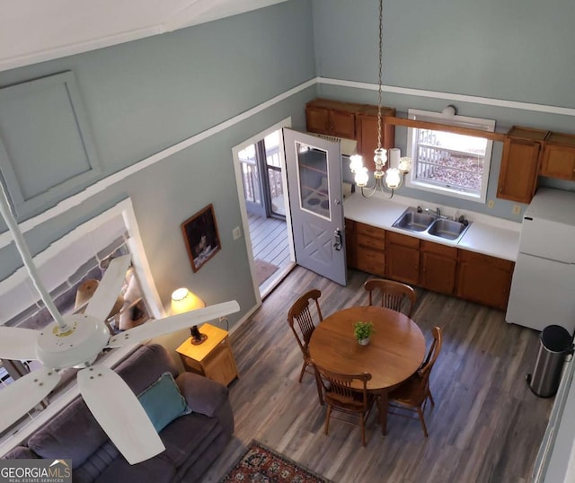 interior space with dark wood finished floors, brown cabinetry, a chandelier, and a sink