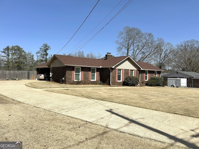 ranch-style home with concrete driveway, brick siding, fence, and a chimney