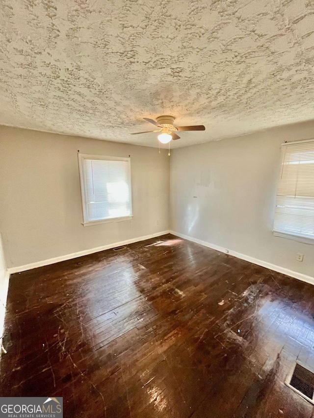 unfurnished room featuring a ceiling fan, baseboards, a textured ceiling, and hardwood / wood-style floors