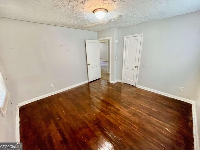 unfurnished bedroom with a textured ceiling, baseboards, and wood finished floors