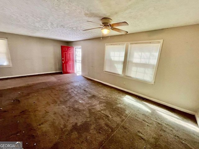 empty room with ceiling fan, a textured ceiling, and baseboards