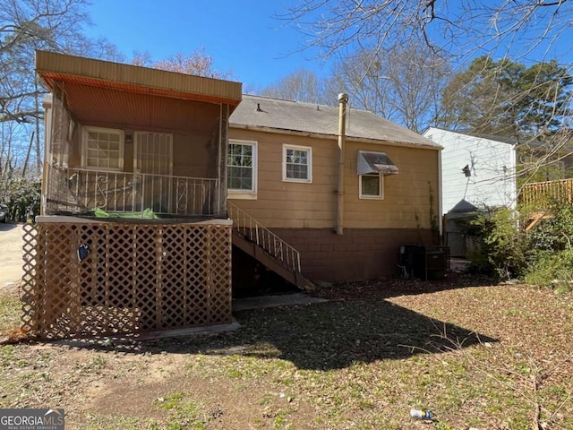 rear view of house with central AC, stairway, and a sunroom