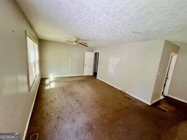 empty room with visible vents, ceiling fan, a textured ceiling, and baseboards