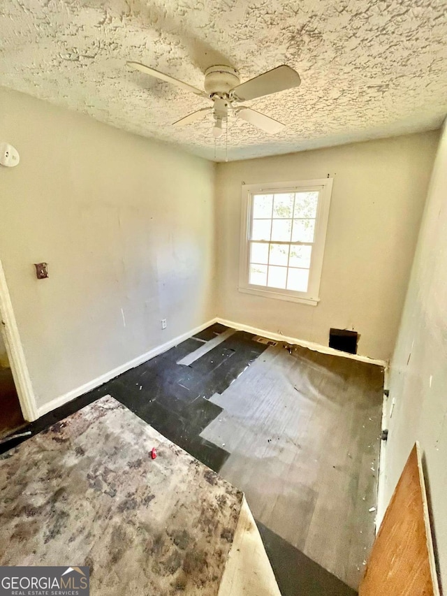 empty room featuring ceiling fan and baseboards