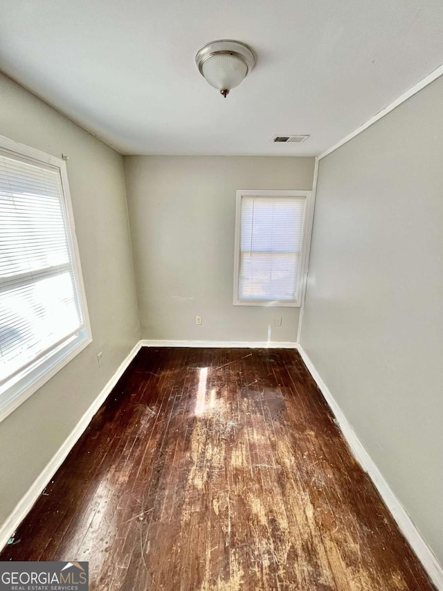 unfurnished room with baseboards, visible vents, and hardwood / wood-style floors