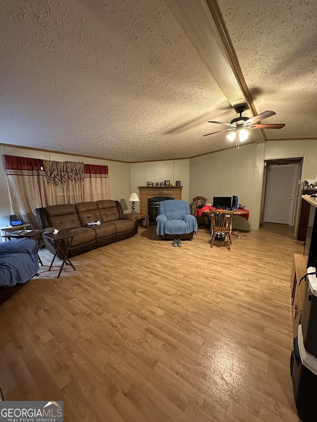 living room with light wood-style flooring, a tiled fireplace, ceiling fan, a textured ceiling, and beamed ceiling