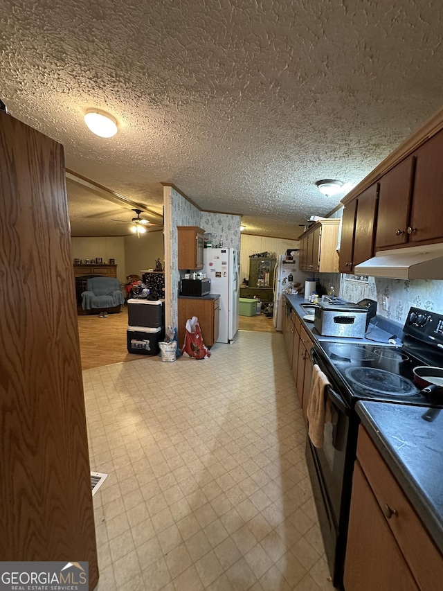 kitchen featuring light floors, stainless steel microwave, black range with electric stovetop, freestanding refrigerator, and under cabinet range hood