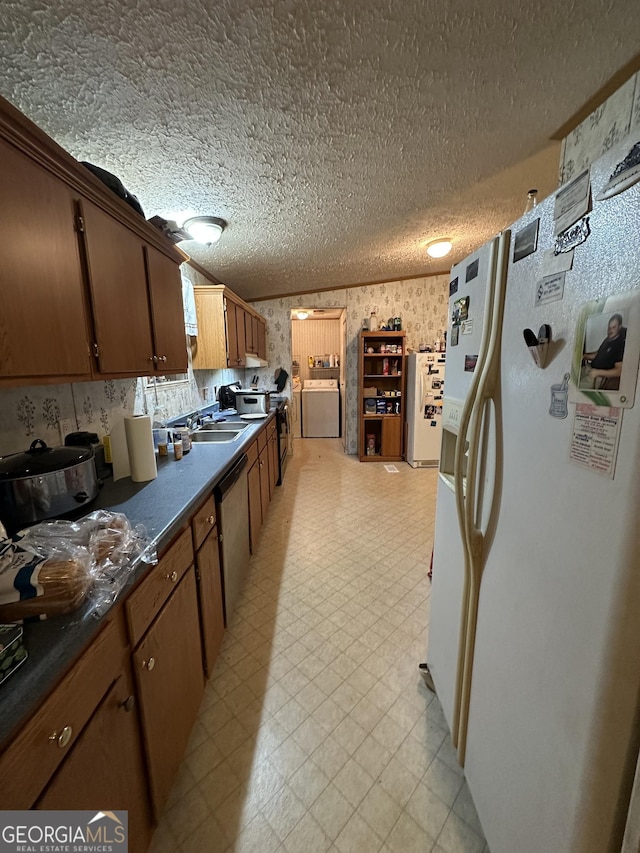 kitchen with white refrigerator with ice dispenser, independent washer and dryer, light floors, dark countertops, and wallpapered walls