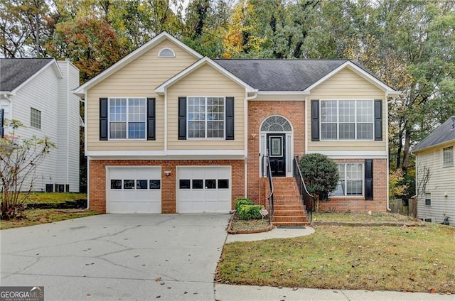 split foyer home featuring driveway, an attached garage, a front yard, and brick siding