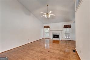 unfurnished living room with a fireplace, a ceiling fan, vaulted ceiling, and wood finished floors