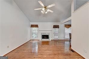 unfurnished living room featuring a fireplace, vaulted ceiling, a ceiling fan, and wood finished floors