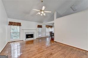 unfurnished living room featuring vaulted ceiling, a fireplace, wood finished floors, and a ceiling fan