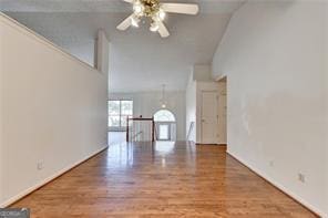 unfurnished living room featuring a ceiling fan, high vaulted ceiling, and wood finished floors