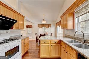 kitchen featuring range hood, light countertops, a sink, a peninsula, and white gas range oven