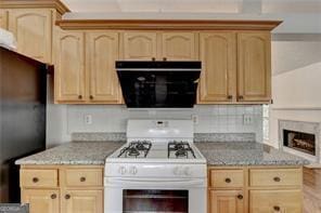 kitchen featuring light stone counters, freestanding refrigerator, light brown cabinets, and white range with gas cooktop