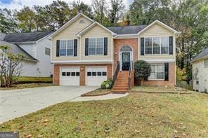 raised ranch featuring an attached garage, a front lawn, and concrete driveway