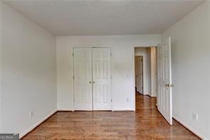 unfurnished bedroom featuring a closet, baseboards, and wood finished floors