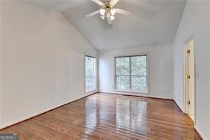 unfurnished room with lofted ceiling, wood finished floors, and a ceiling fan