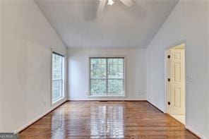 empty room with a ceiling fan, vaulted ceiling, and wood finished floors