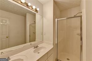 bathroom with double vanity, a stall shower, and a sink