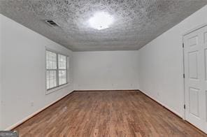 bonus room with visible vents, a textured ceiling, and wood finished floors